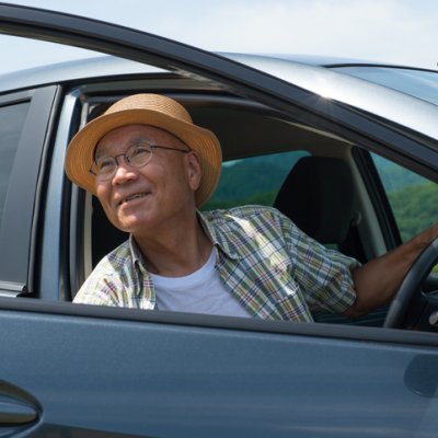 A man wearing a hat looks out the open door of a car.